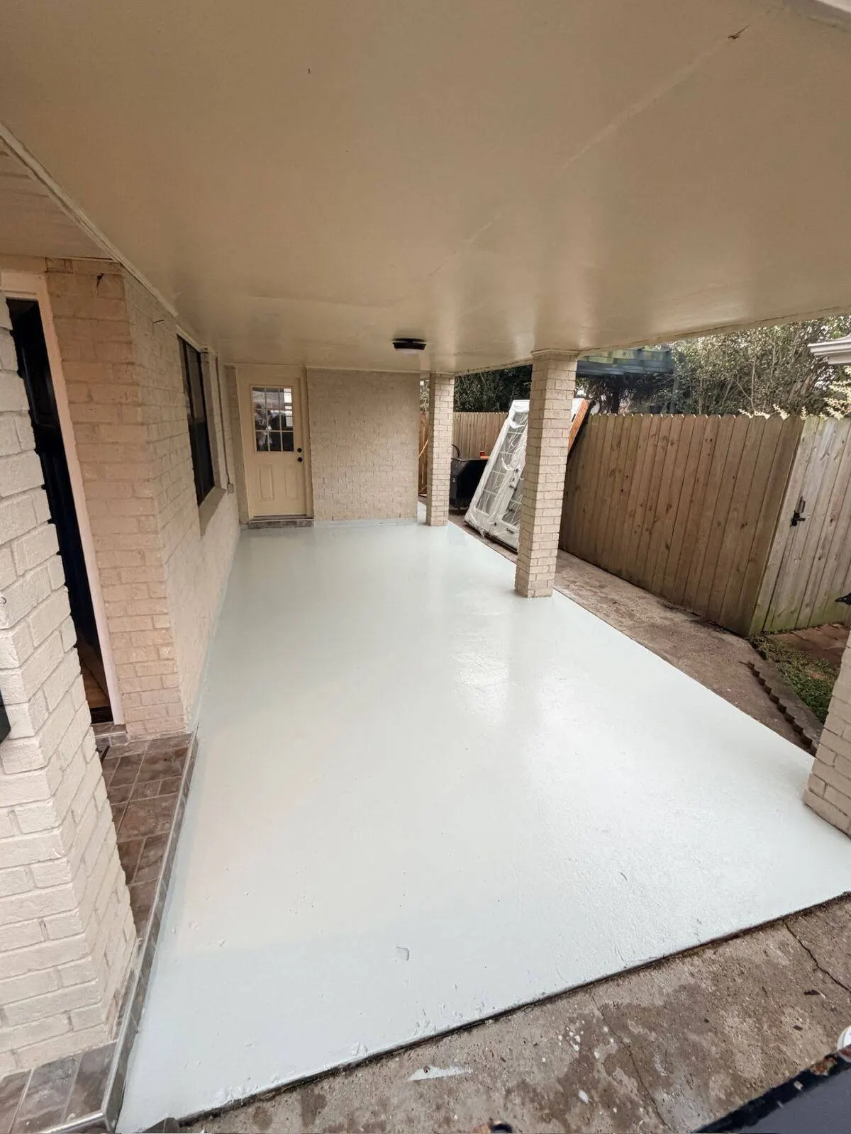 Covered patio epoxy floor installation with white coating in Metairie LA