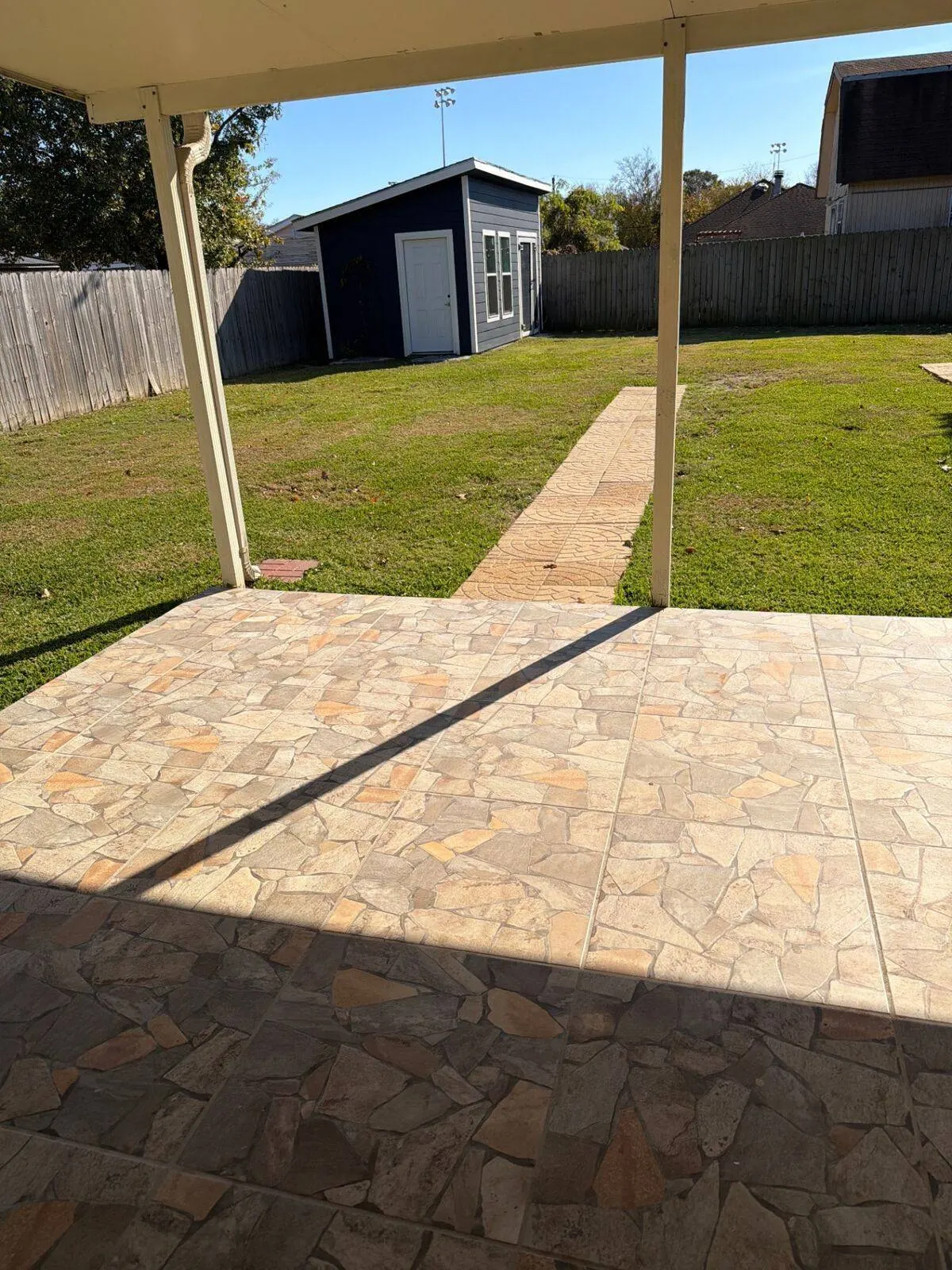 Covered patio with flagstone tile and walkway to outbuilding in Metairie LA