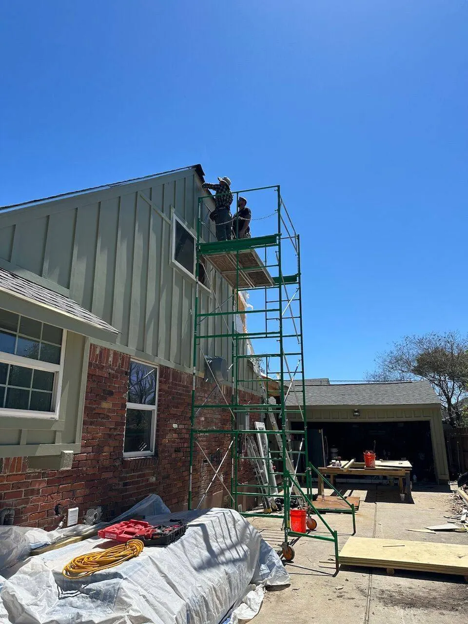 Cajun Home Services crew on scaffolding finishing exterior siding