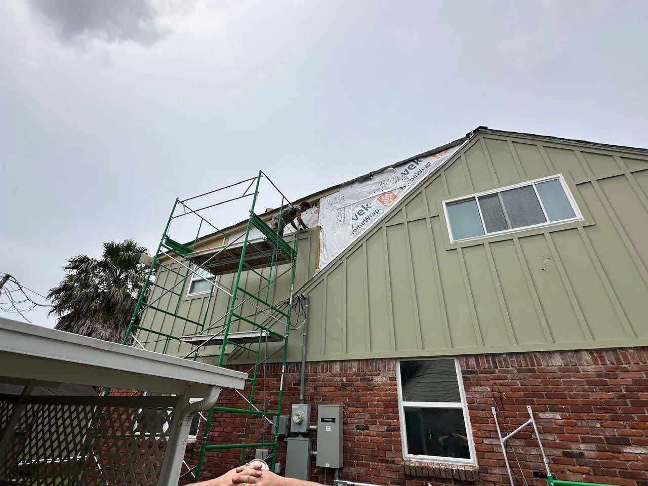 Crew installing gable-end siding from scaffolding on Louisiana home