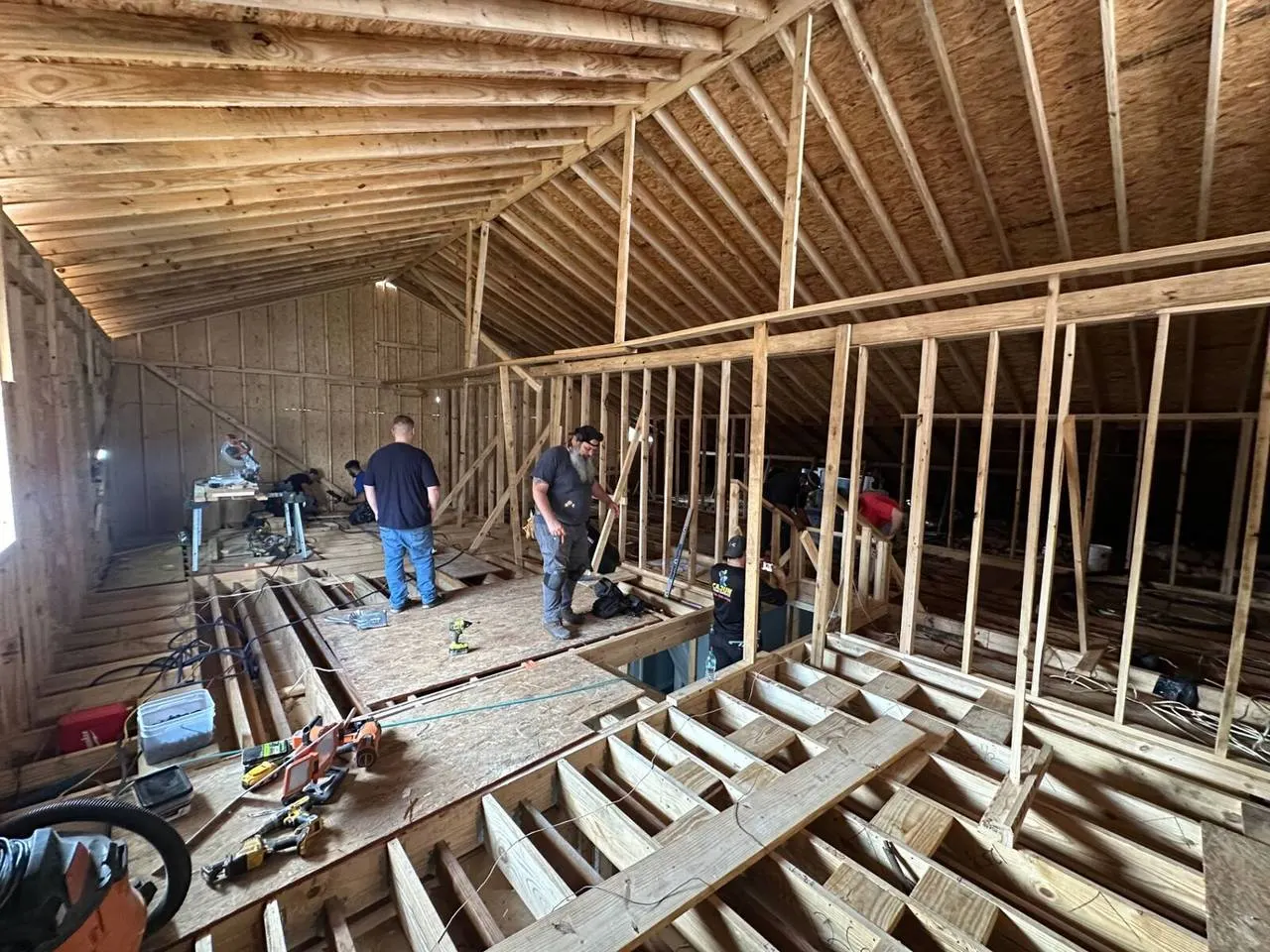 Crew framing interior walls on second floor addition with roof rafters in Metairie
