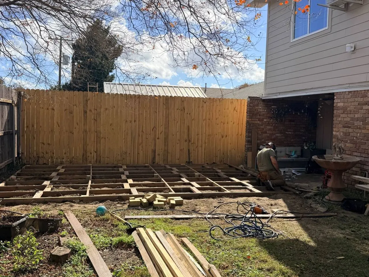 Crew installing deck floor joist framing in Metairie residential backyard