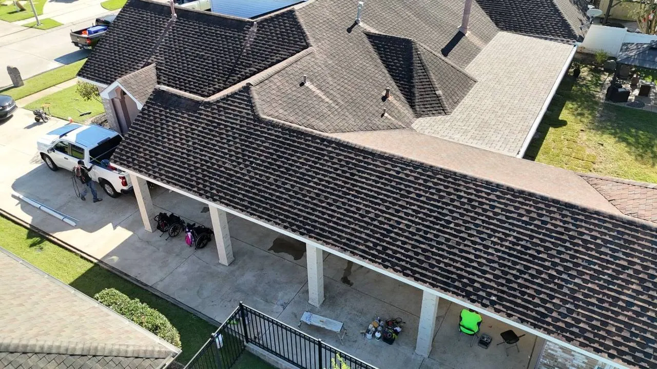 Aerial view of shingle roof with covered patio and jobsite crew in Destrehan, Louisiana