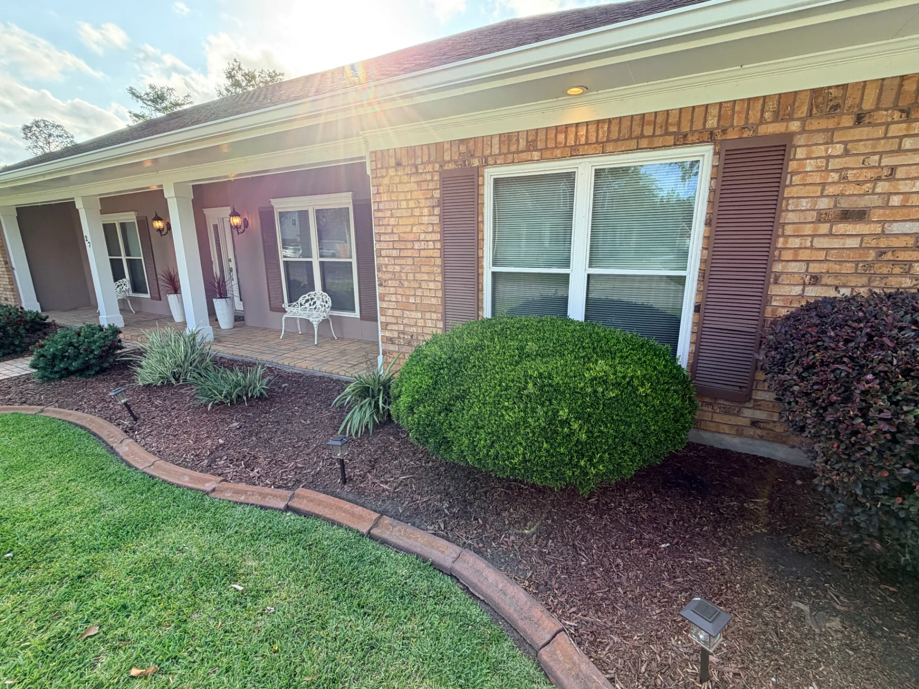 Worn brown exterior shutters with sun damage on Destrehan brick home before replacement