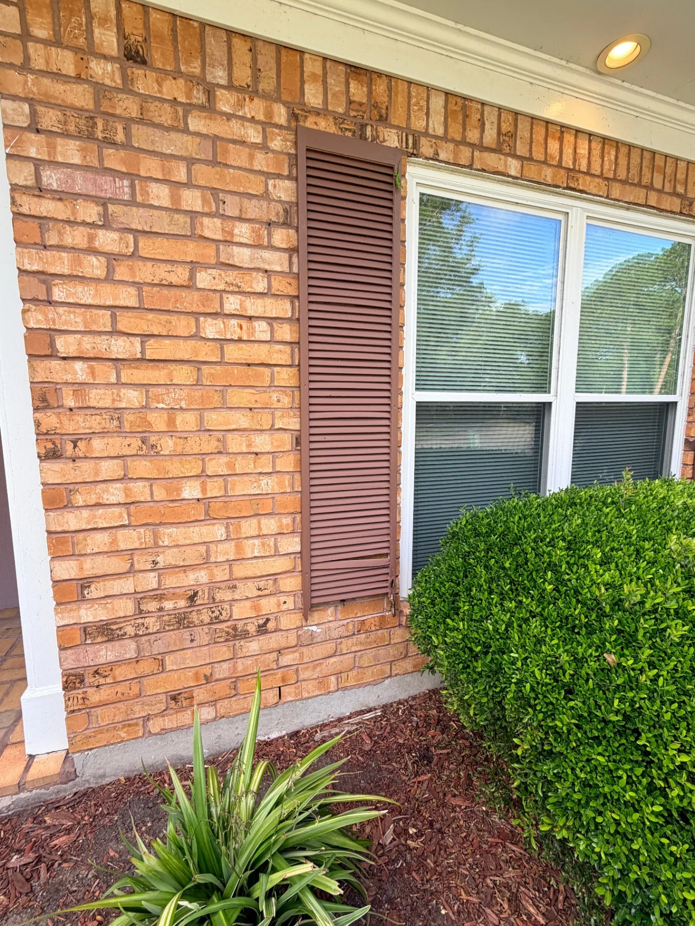 Close-up of faded and damaged louvered shutter on Destrehan Louisiana brick exterior