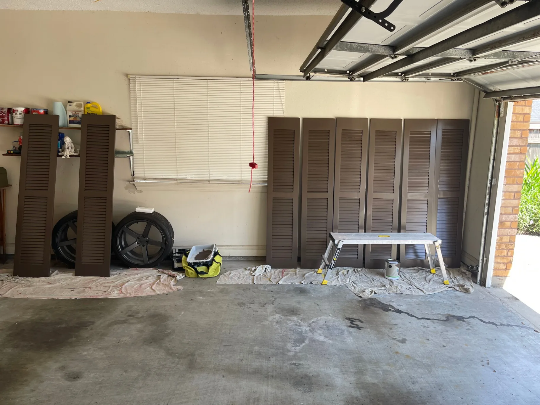 New exterior shutters laid out on drop cloths being hand-painted in Destrehan Louisiana garage