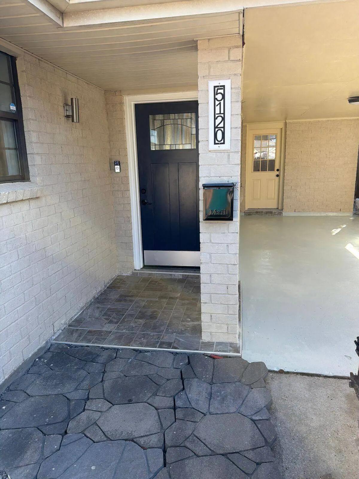 New front entry door with stamped concrete and carport coating at Metairie home