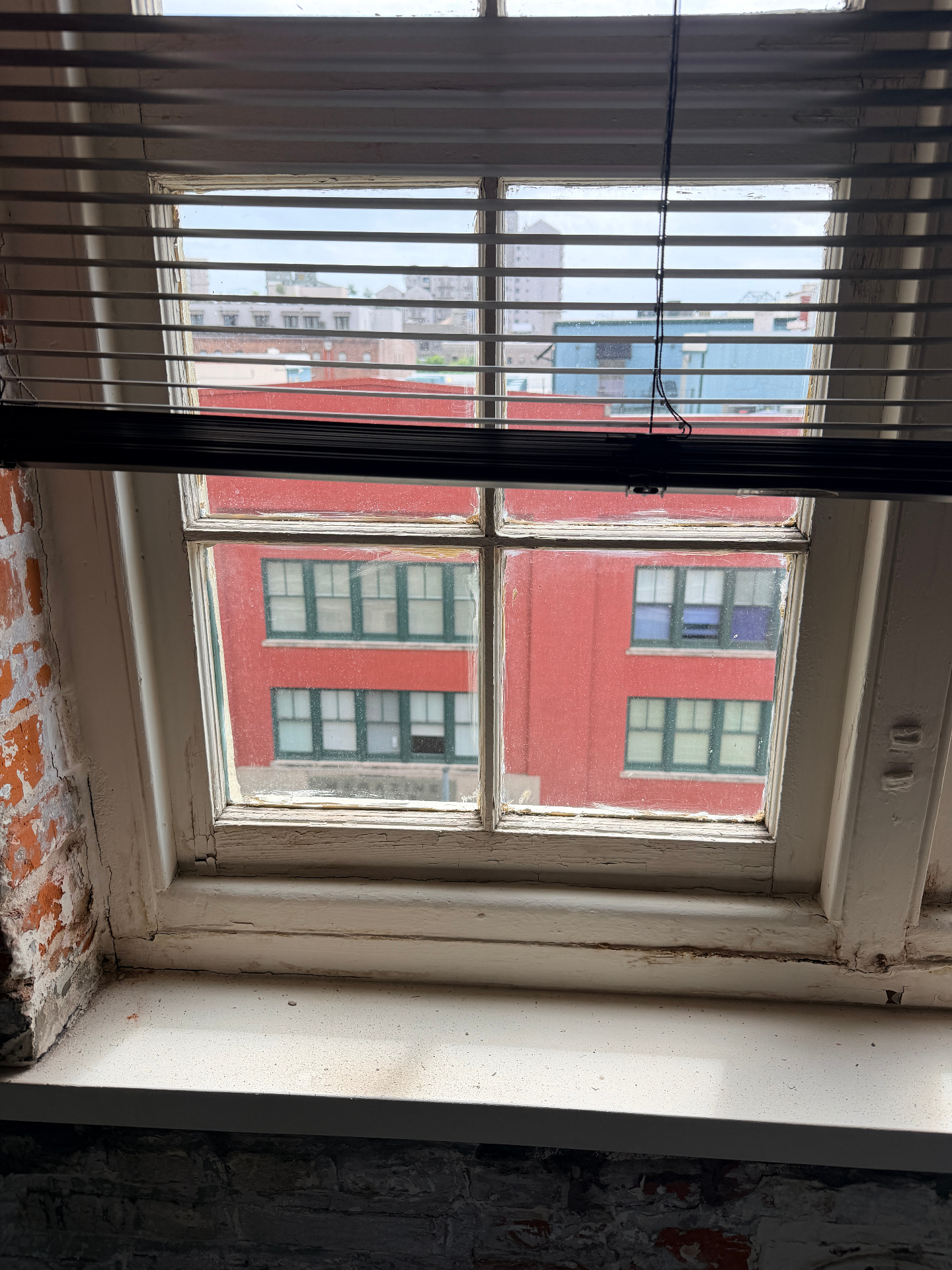 Before restoration view through dirty historic divided-light wood window in the New Orleans Arts District