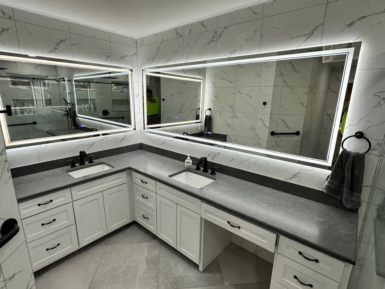 Luxury double vanity bathroom remodel with LED mirrors and marble tile walls in Metairie LA