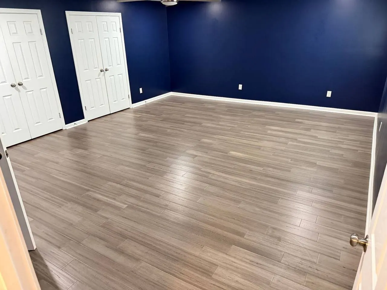 Luxury vinyl plank LVP flooring installation in Gretna Louisiana with gray wood-look planks and navy blue walls