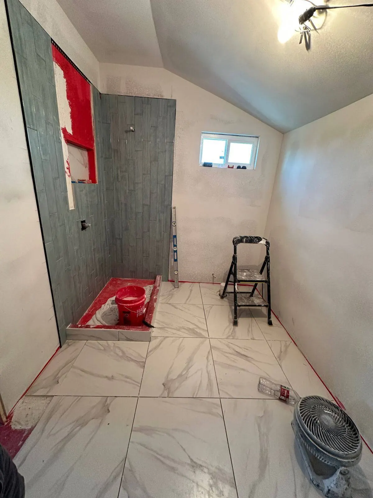 Master bathroom tile installation in progress with marble floor in Metairie addition