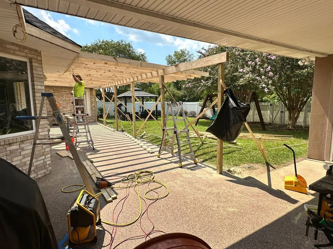 Crew installing patio roof framing on brick home in Destrehan, St. Charles Parish