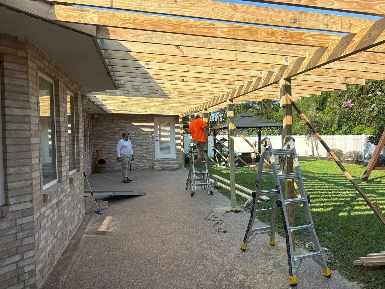 Crew framing covered patio addition with pressure-treated lumber in River Ridge Louisiana