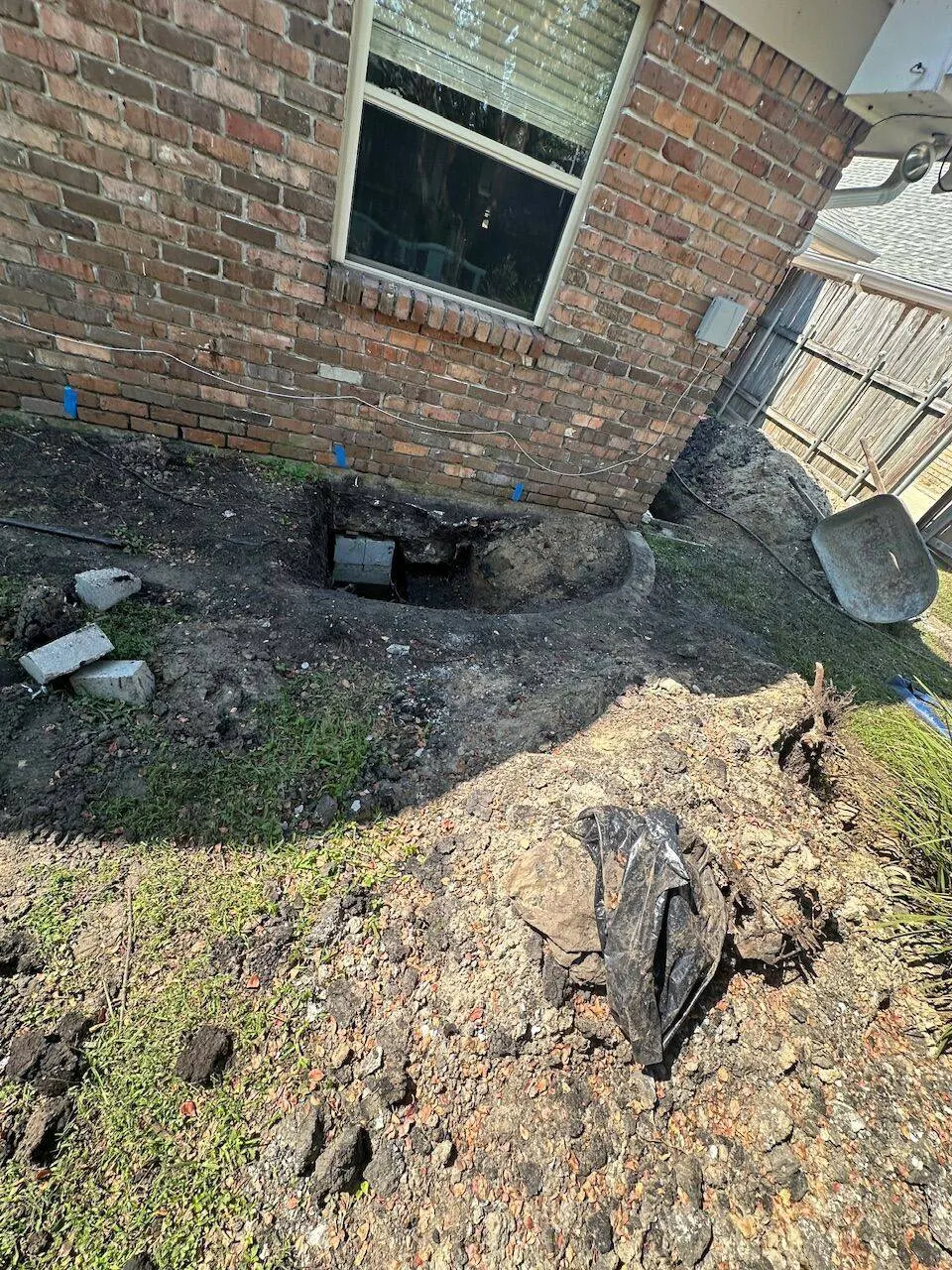 Corner foundation pier excavation at brick home showing clay soil conditions in Jefferson Parish