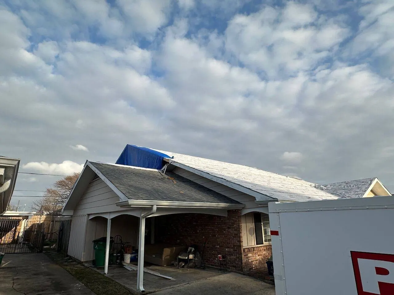 Emergency roof tarp protecting home during repair work after storm damage