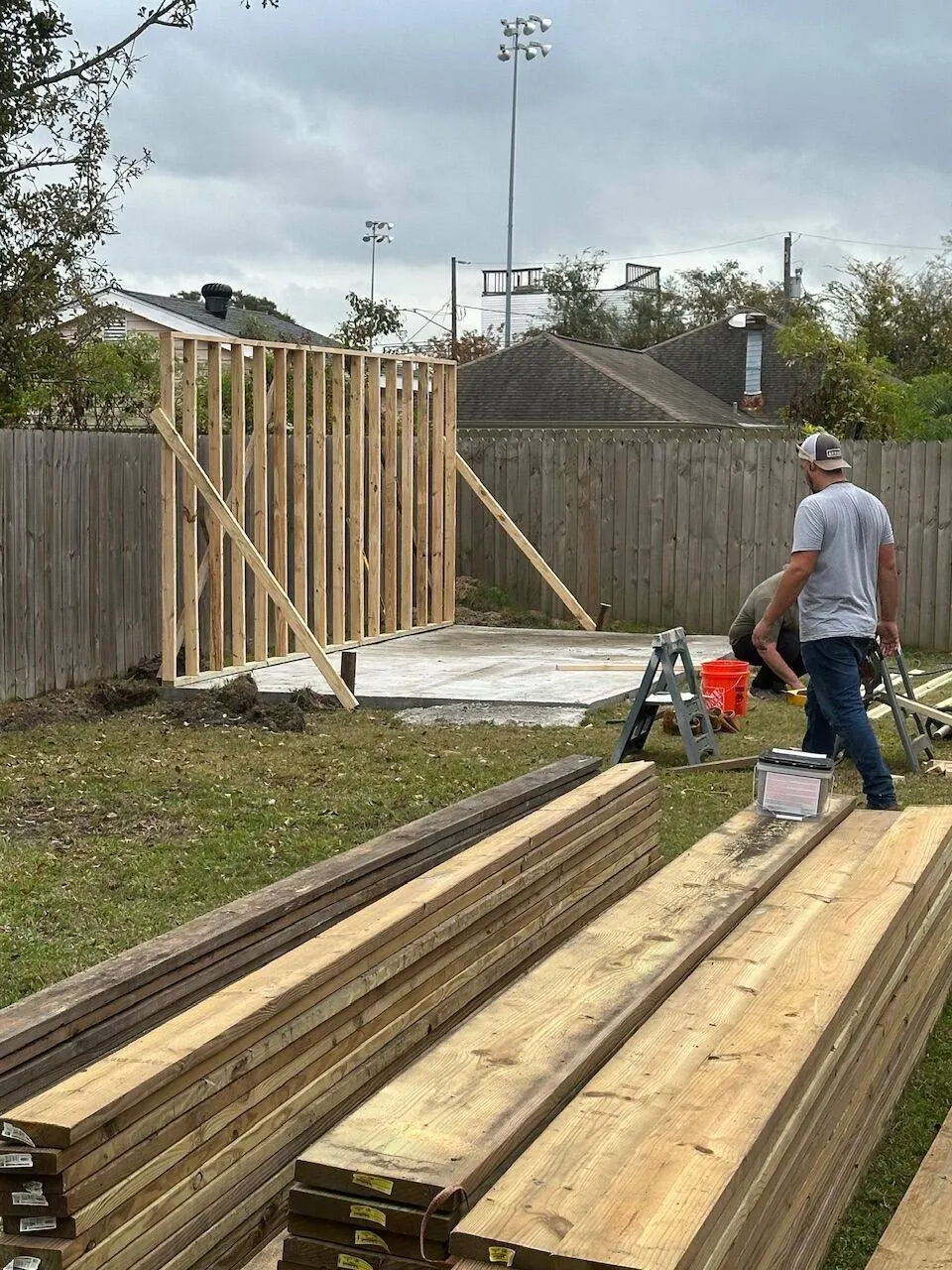 Crew framing walls on new concrete slab for outbuilding construction in Metairie