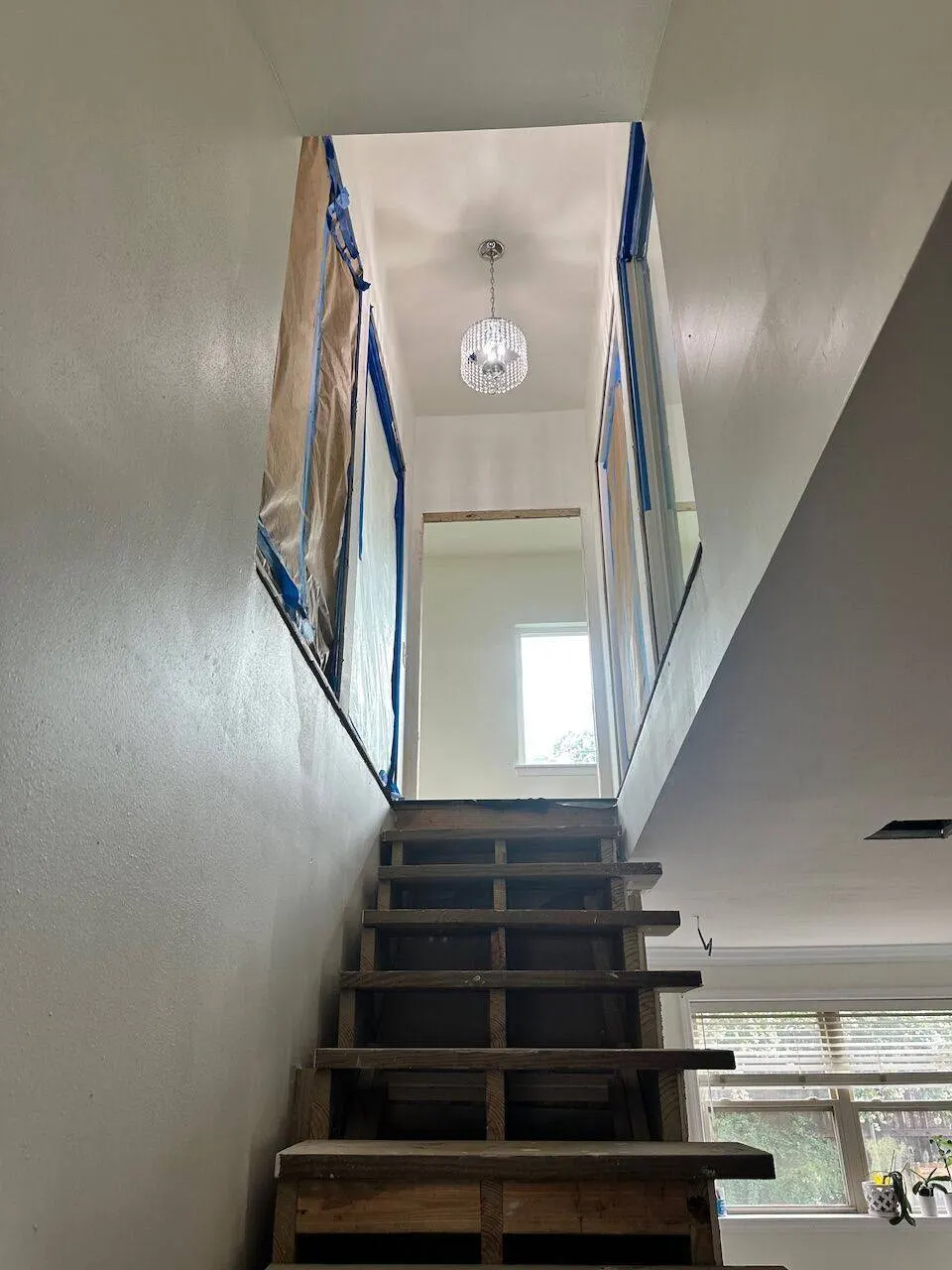 Stairwell with glass wall panels and crystal chandelier in Metairie master bedroom addition