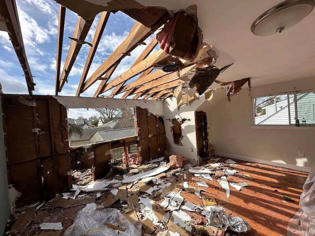 Storm damage to roof and interior showing exposed rafters requiring structural repair