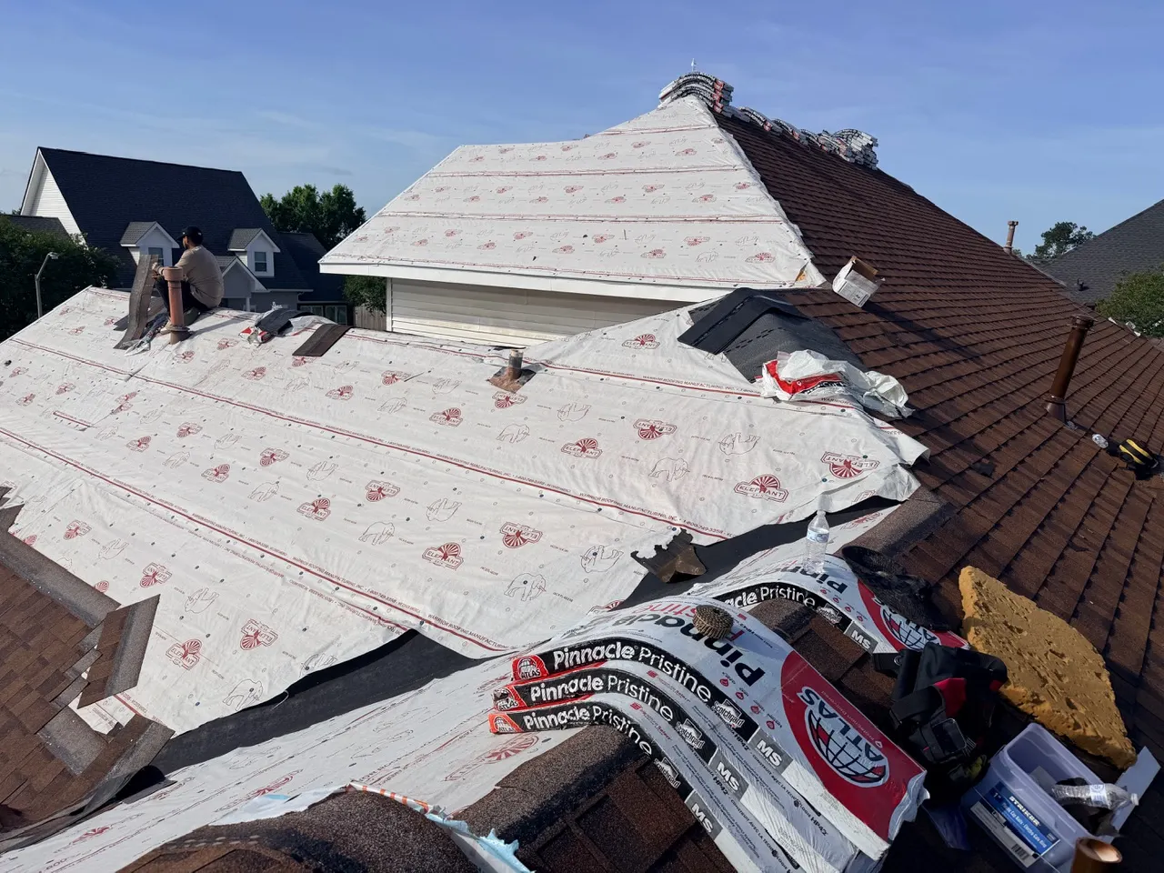 Crew installing Atlas synthetic roof underlayment over fresh decking on a Destrehan shingle roof replacement before architectural shingle install