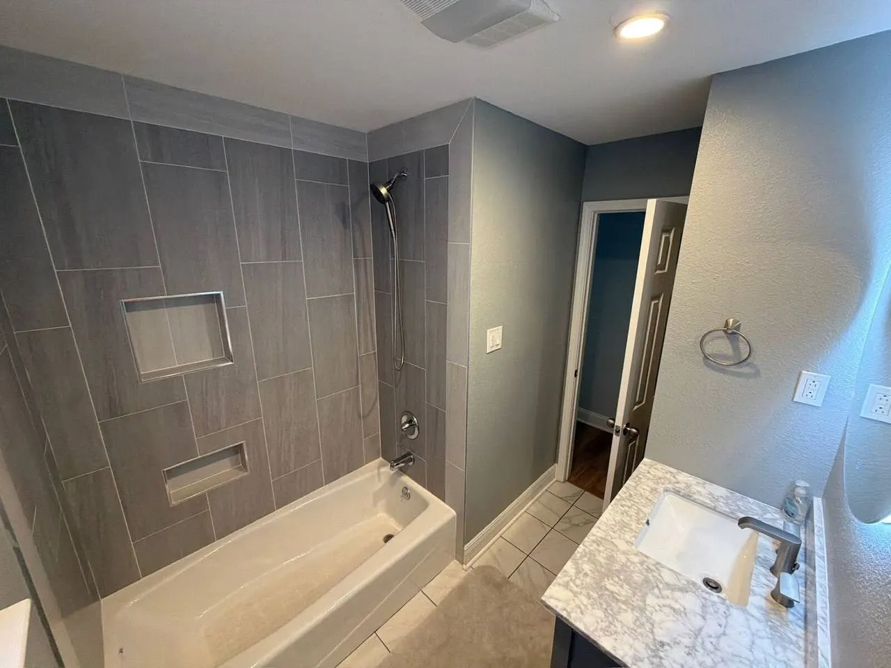Tile tub surround bathroom remodel with gray wood-look tile and niches in Metairie LA