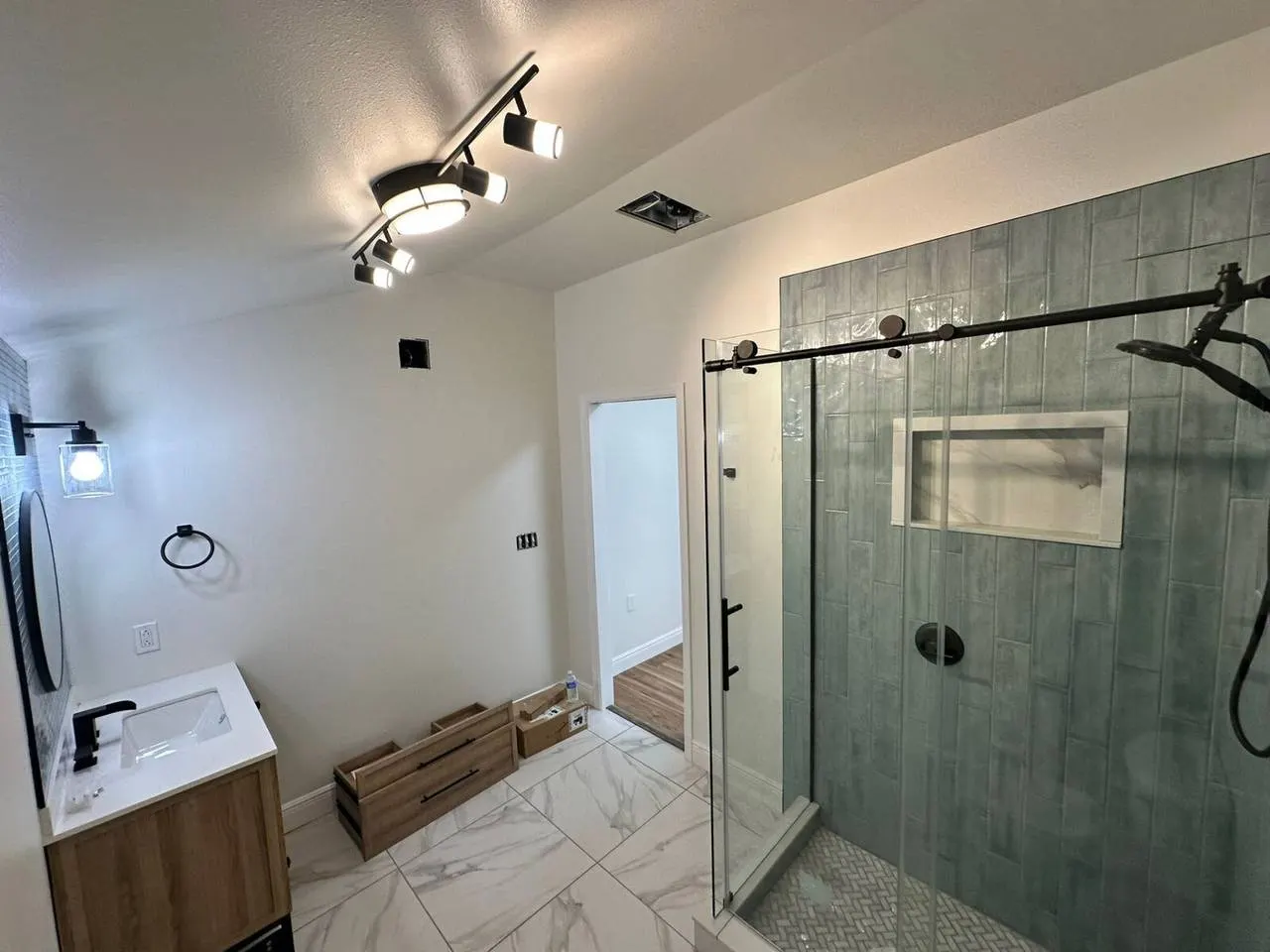 Walk-in shower remodel with sliding glass door and green tile in Metairie LA